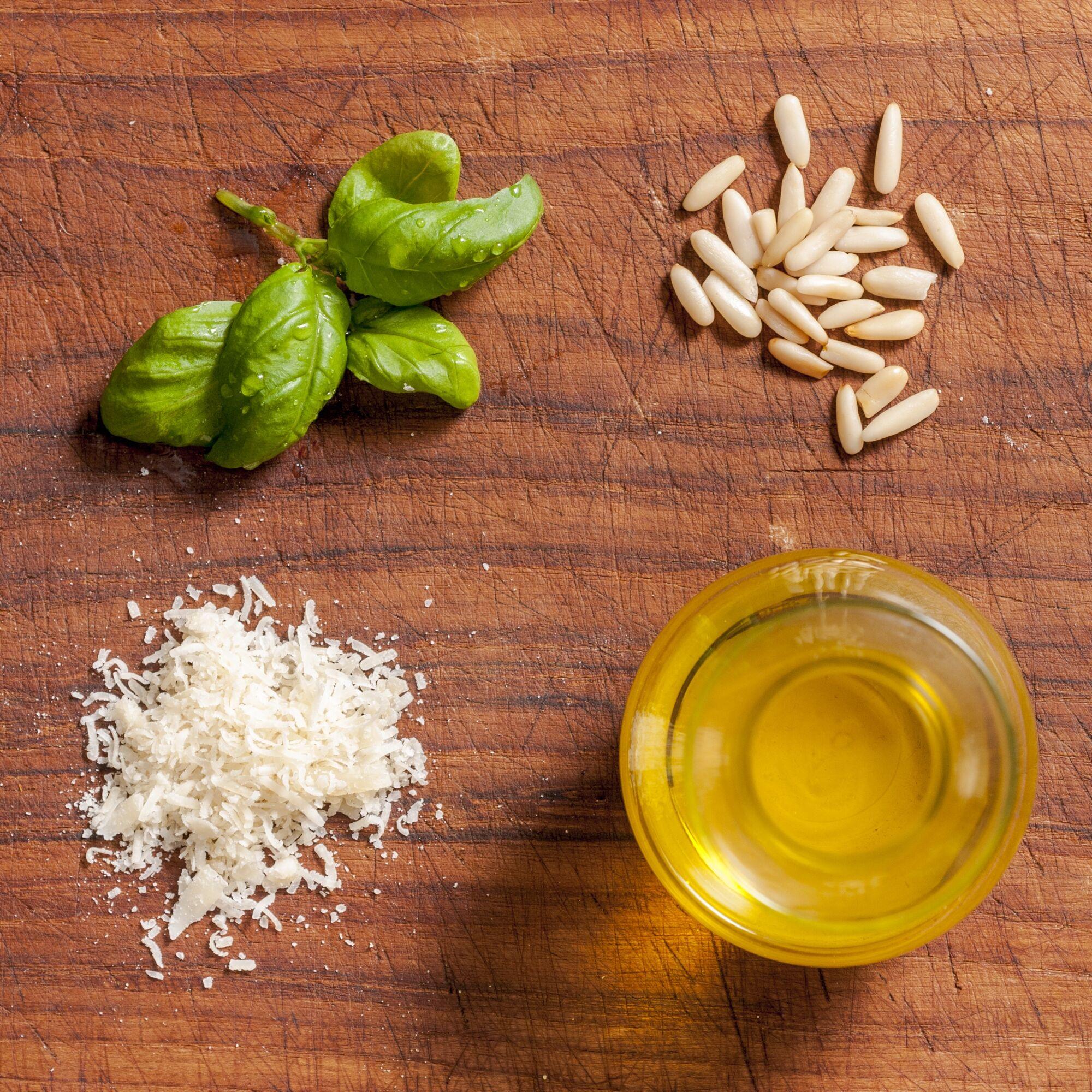Foodfotografie: Basilikum, Pinienkerne, Parmesan und Olivenöl auf einem Holzbrett