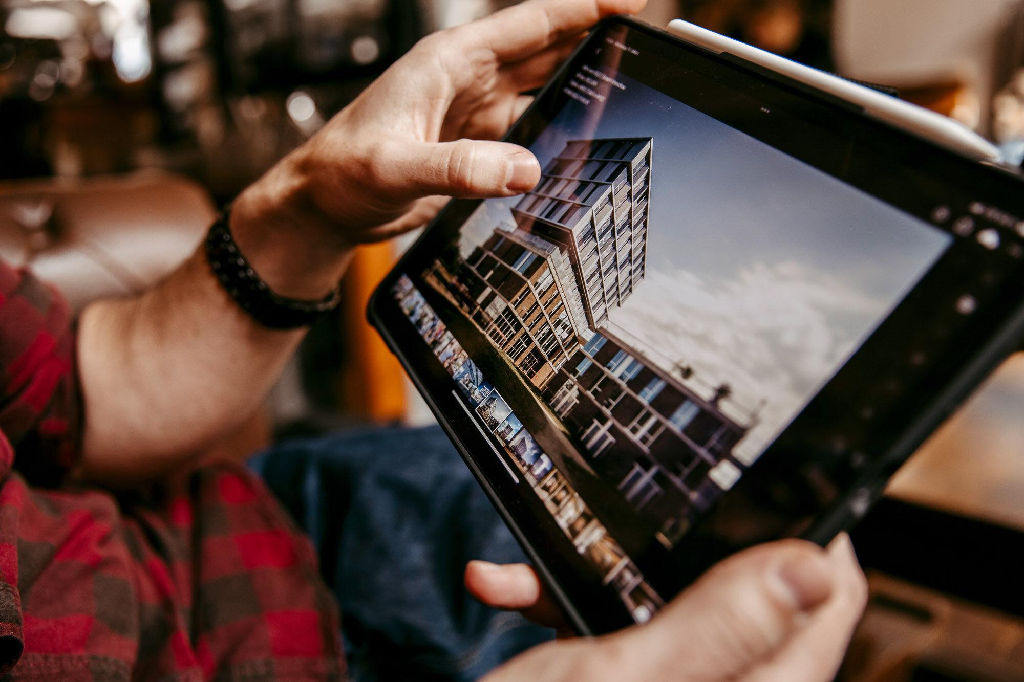 Hände halten ein Tablet mit einer Architekturaufnahme bei der Bildkontrolle