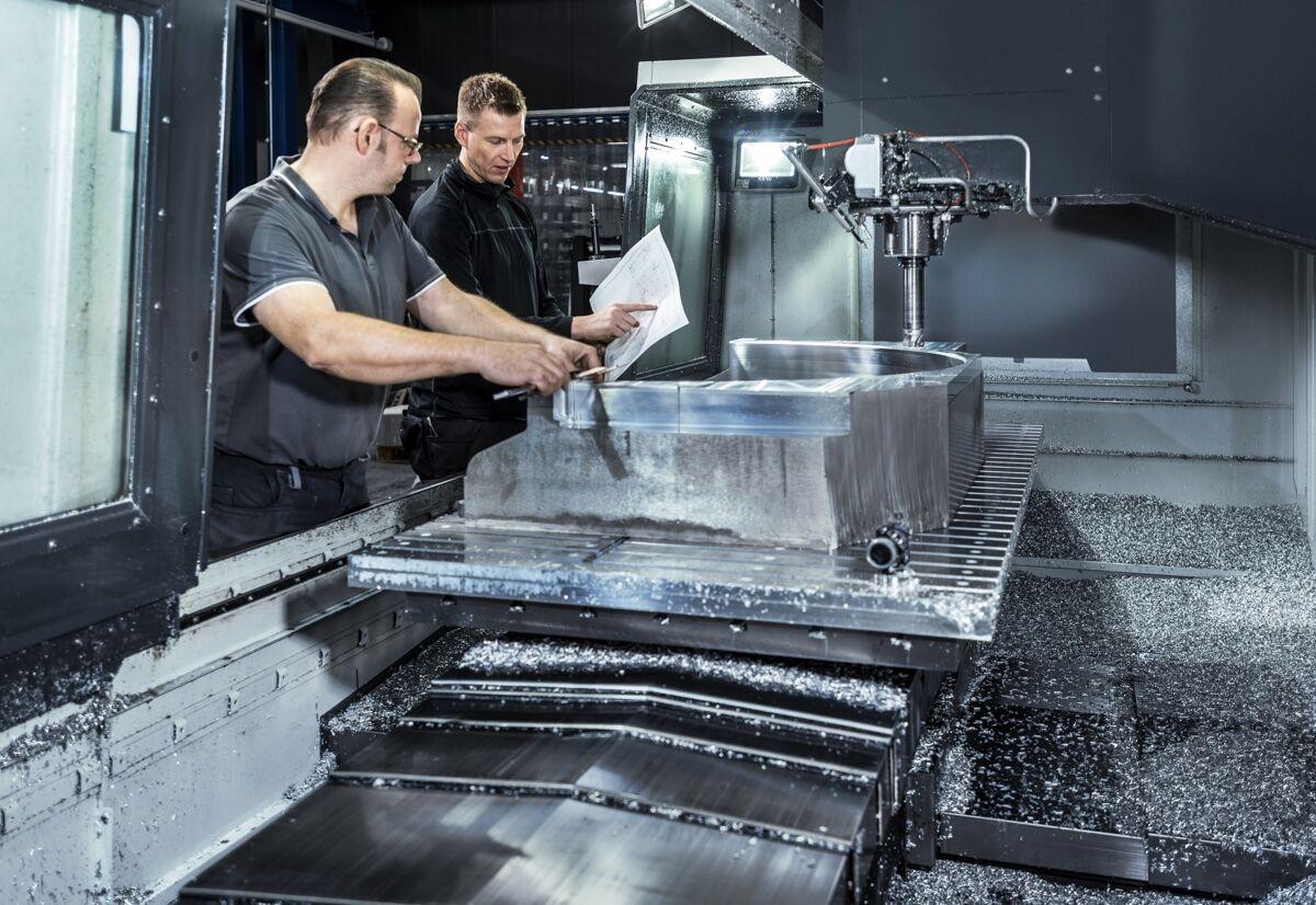 Industriefotografie: Mitarbeiter richten ein Werkstück in einer Fräsmaschine ein