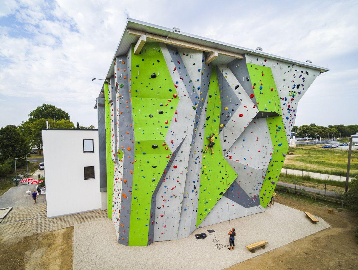 Luftaufnahme per Drohne: Außenkletterturm mit grünen Kletterwänden an einer Kletterhalle