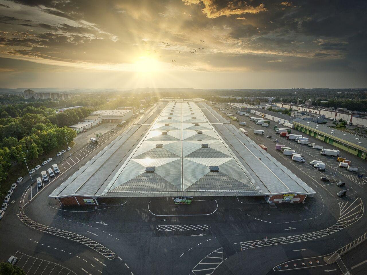 Drohnenaufnahme eines großen Logistikzentrums mit Glasdach im Abendlicht