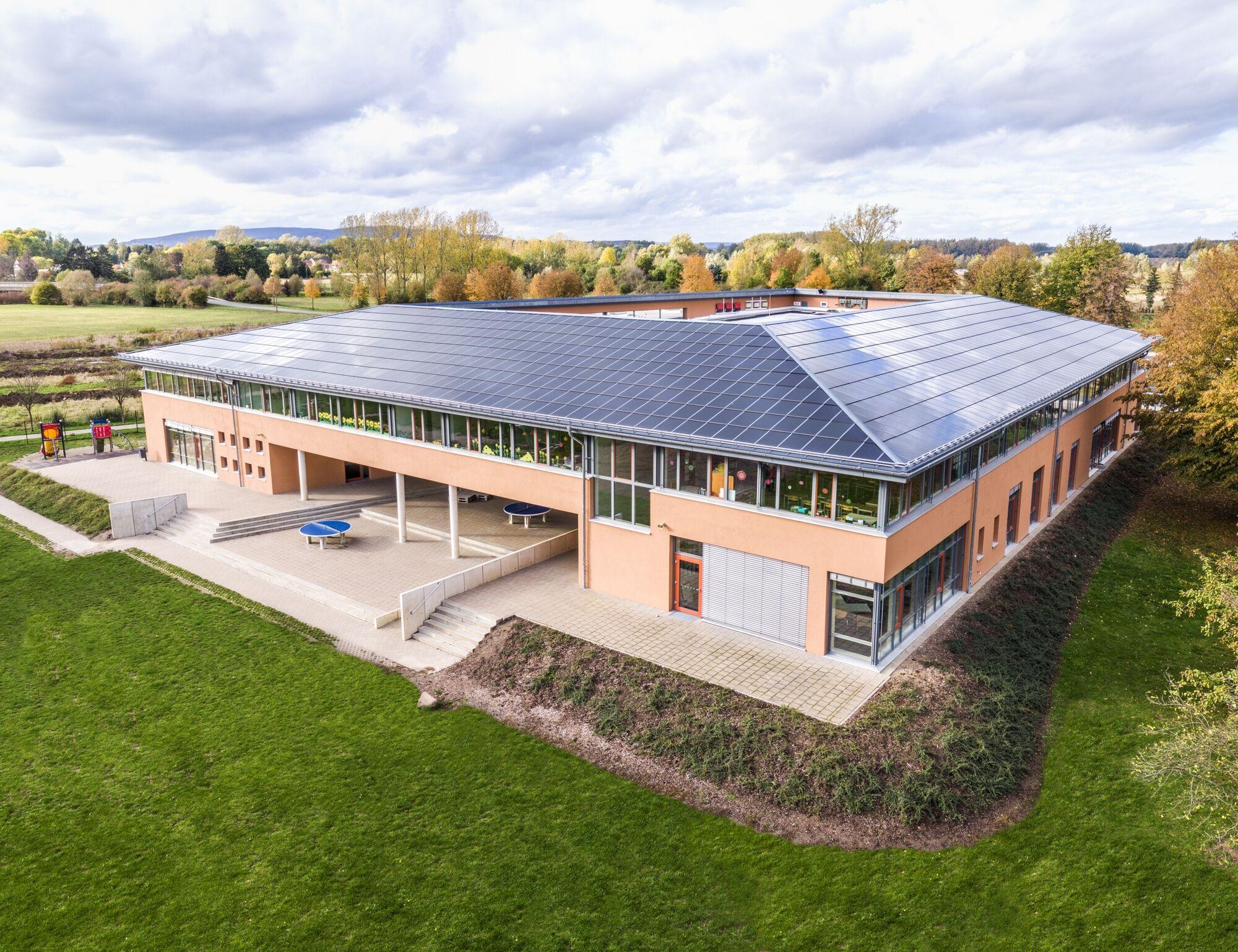 Luftaufnahme per Drohne: Schulcampus mit Solardach und Sportplatz im Herbst