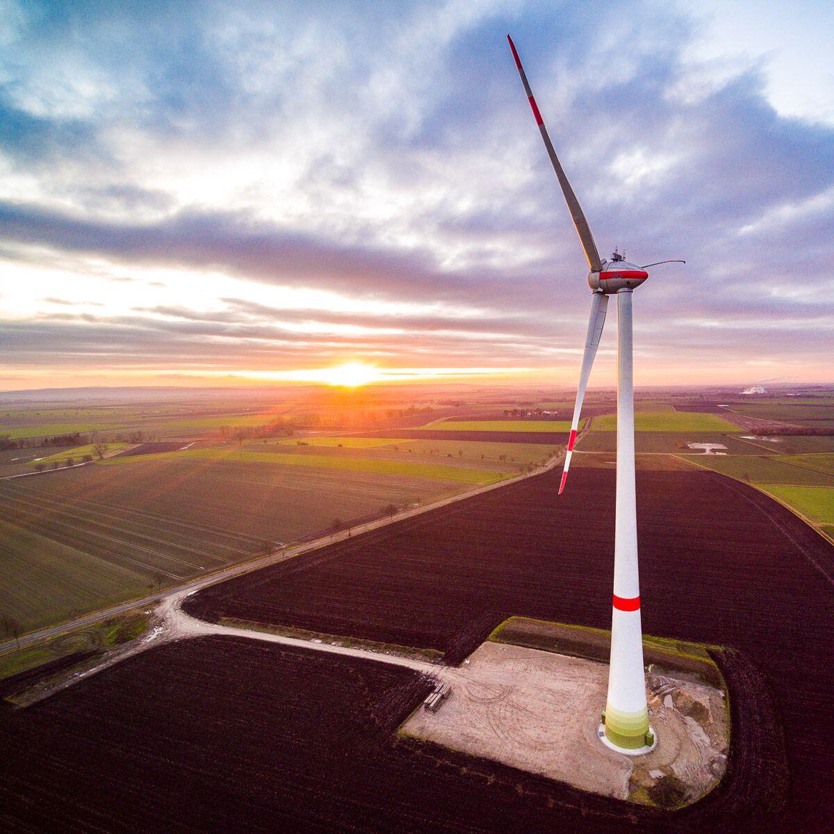 Luftaufnahme per Drohne: Windkraftanlage auf einem Feld bei Sonnenuntergang