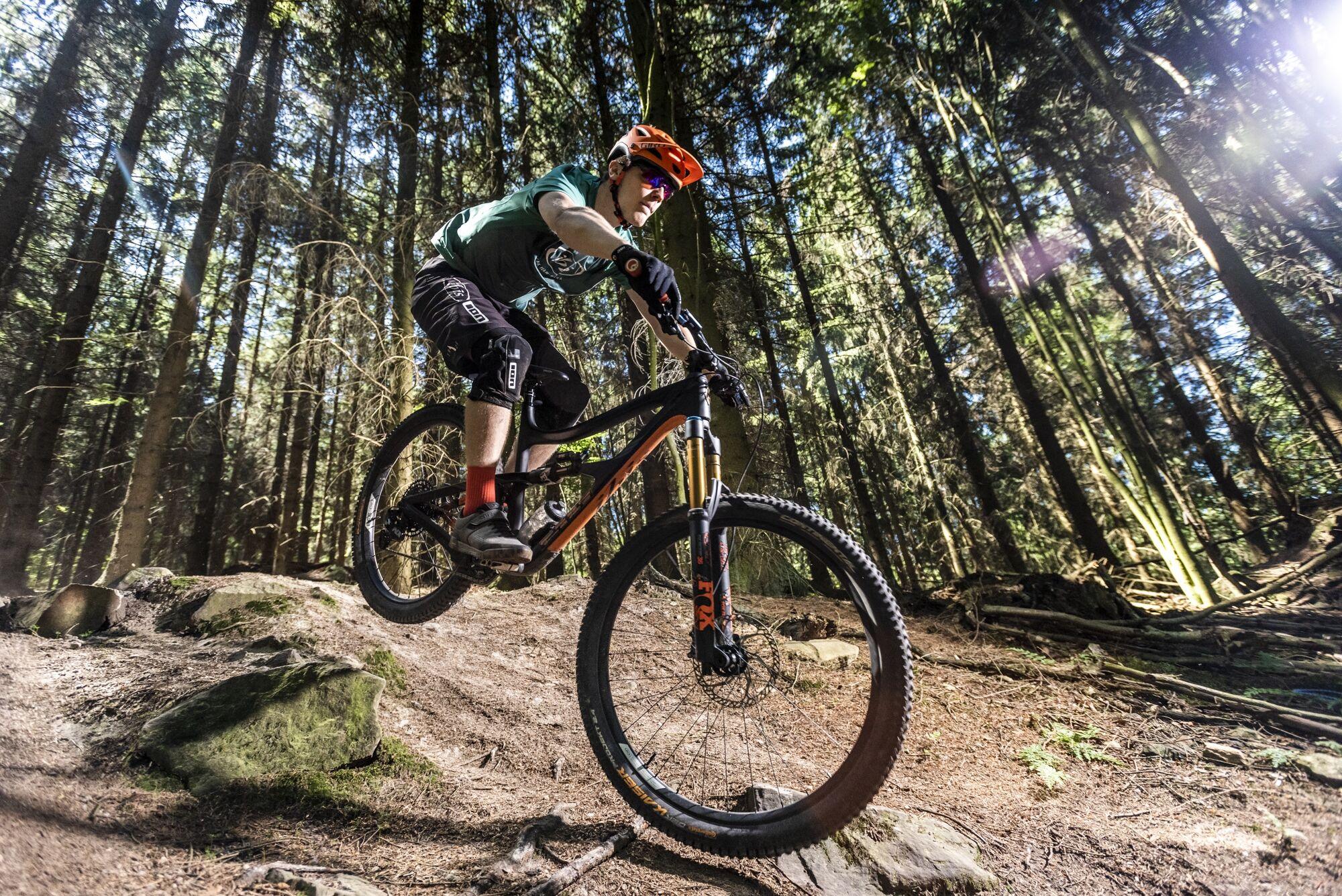 Outdoorfotografie: Mountainbiker fährt über einen Trail im Wald