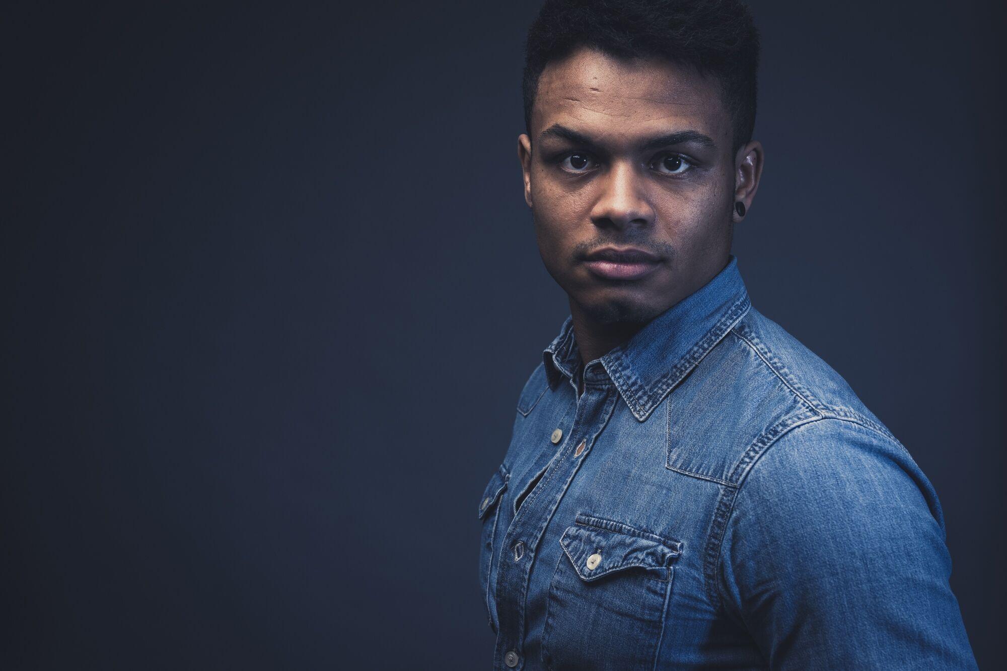 Portraitfotografie im Studio: Mann im Jeanshemd vor dunklem Hintergrund