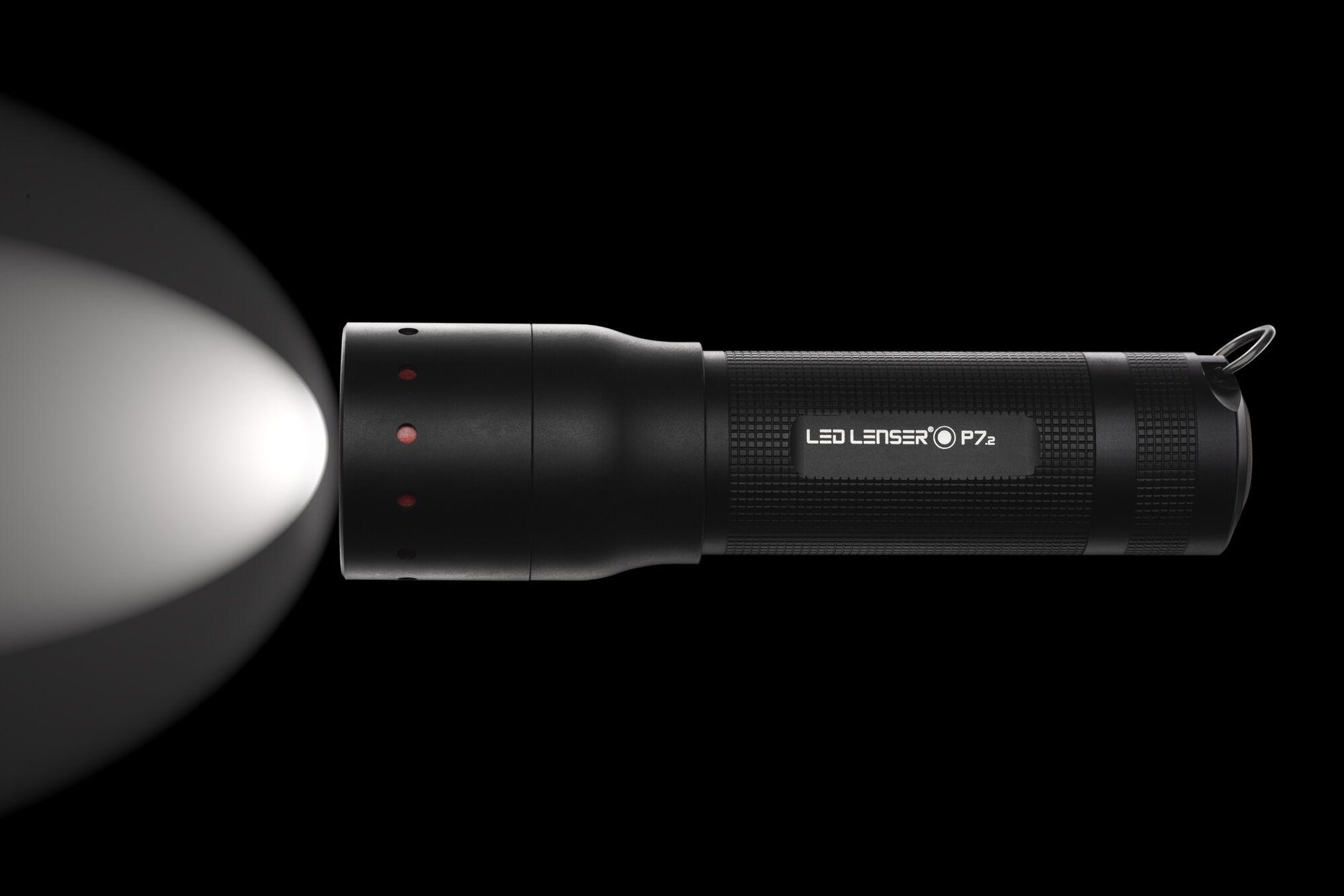 Produktfotografie: schwarze Taschenlampe mit Lichtkegel vor dunklem Hintergrund